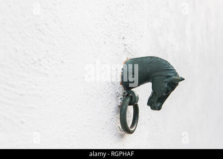 Side view of black decorative figure of horse with ring on white stone wall of building in Pyrenees Stock Photo