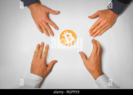 arms of business men reaching for bitcoin - people wanting to buy bitcoin Stock Photo