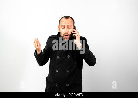 Middle-aged man with overcoat screams angrily at his mobile phone, isolated on white. Stock Photo