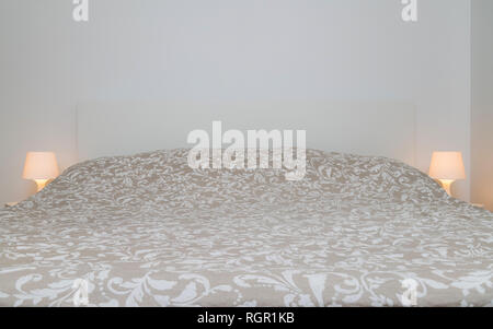Front of the bed with bed sheets and pillows in sleeping room with bed lights on the sides. Comfort, choosing mattress for sleeping Stock Photo