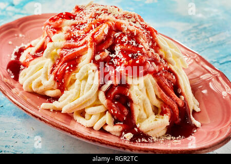 Spaghetti icecream dessert with strawberry fruit sauce in close up view Stock Photo