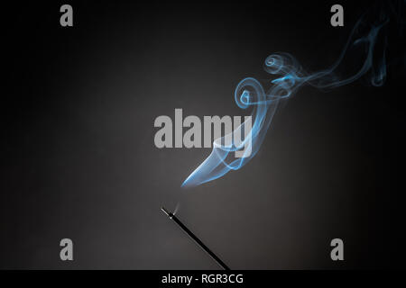 Smoking incense stick with smoke going up on Black Background. Pure relaxation theme, smoke steam, smoke waves, fog and mist effect Stock Photo