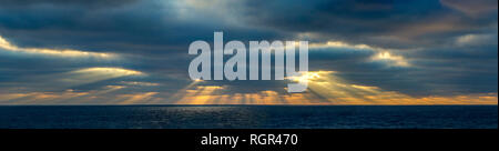 Panoramic of Suns rays coming from behind clouds as the sun is setting over the North Atlantic. Stock Photo