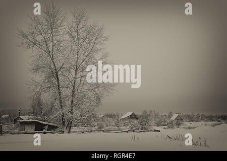 several snow-covered houses with triangular roofs, a large tree on the left, an empty sky, beige-black colors Stock Photo