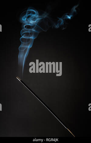 Smoking incense stick with smoke going up on Black Background. Pure relaxation theme, smoke steam, smoke waves, fog and mist effect Stock Photo