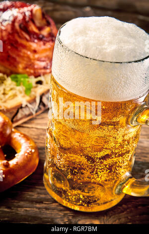 Mug of pale beer with thick foam in close up against wooden table Stock Photo