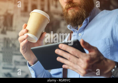 Businessman using digital tablet and drinking coffee. Smartphone Paper Cup Shirt Beard. Office Coffee Break Concept Stock Photo