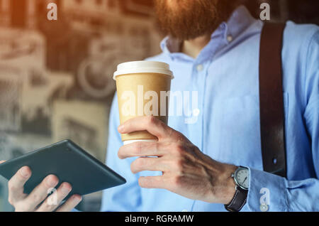 Businessman using digital tablet and drinking coffee. Smartphone Paper Cup Shirt Beard. Office Coffee Break Concept Stock Photo