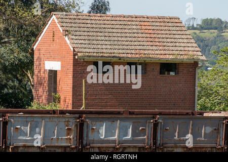 A close up view of a small old abandoned building and a rusted railway carrage that is no longer being used and that has rusted with concrete pillers  Stock Photo