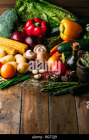 Assorted fresh vegetables and bottle of oil lying on timber tabletop Stock Photo