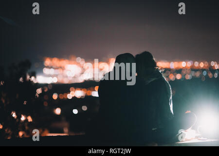 Back view of young man and Woman hugging and admiring wonderful night city together Stock Photo