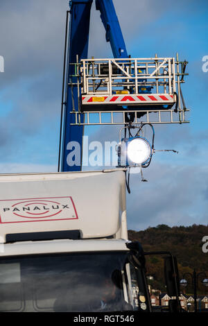 Filming on Location: An Arri 18k HMI fresnel lighting unit , on hire from Panalux film and television lighting company,  suspended from a cherry-picker elevated platform, on a film location , UK Stock Photo