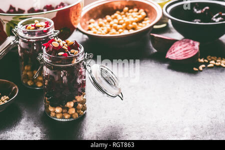 Healthy homemade beetroot salad with chickpeas and pine nuts in glasses for lunch on dark kitchen table background with ingredients, top view. Purple  Stock Photo
