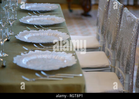Golden bronze elegant table with four seats, ready for a formal event, banquet or wedding, featuring pearly white decorated plates and silverware Stock Photo