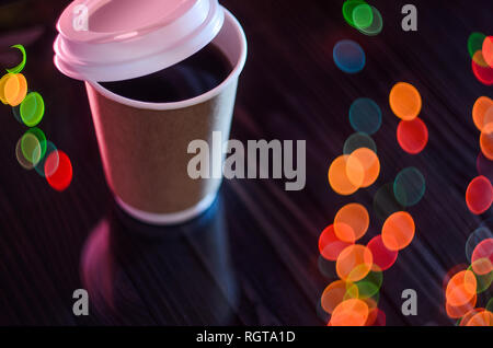 A cup of takeaway coffee on the table. Bokeh lights on background. Concept for mockup, background. Paper cup Plastic Cover Blurred Background Christma Stock Photo