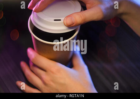 A cup of takeaway coffee on the table. Bokeh lights on background. Hands Paper cup Plastic Cover Blurred Background Christmas Bokeh Stock Photo