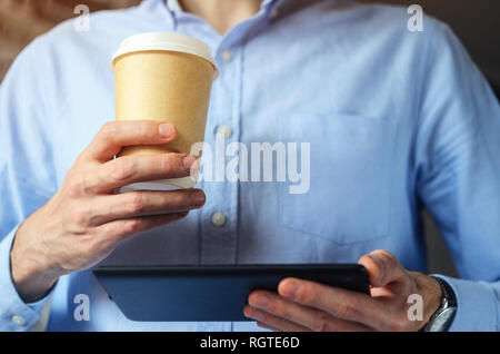 Businessman using digital tablet and drinking coffee. Smartphone Paper Cup Shirt Beard. Office Coffee Break Concept Stock Photo