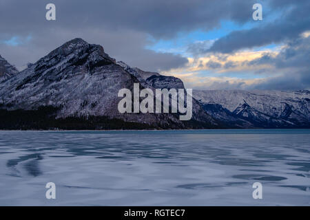 Cloudy colorful skies and winter sunset over mountain peaks at Lake Minnewanka, Banff National Park, Alberta, Canada, 2018 Stock Photo
