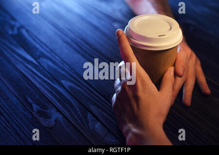 A loving couple at the table. Top view. Hands Paper cup Plastic cap Wooden table Beautiful light Stock Photo