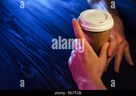 A loving couple at the table. Top view. Hands Paper cup Plastic cap Wooden table Beautiful light Stock Photo