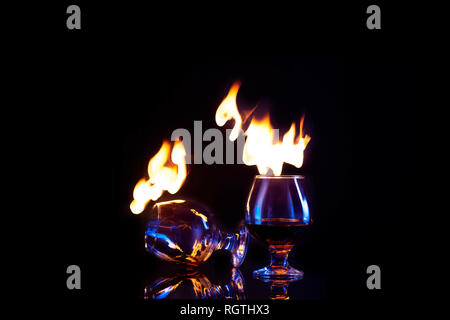 Glasses with burning alcohol on dark background Copy space Stock Photo