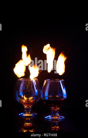 Glasses with burning alcohol on dark background Copy space Vertical Stock Photo
