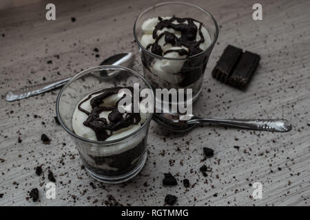 Homemade yogurt of crushed cookies, chocolate and cream with crumbs on the wooden table Stock Photo