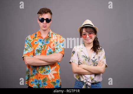 Multi ethnic tourist couple wearing sunglasses and Hawaiian shirt Stock Photo