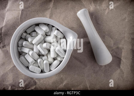 Several pills inside white mortar, conceptual image Stock Photo