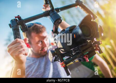 DSLR Digital Video Camera on a Gimbal. Caucasian Cameraman with Motion Picture Camera Installed on Professional Stabilizator. Stock Photo