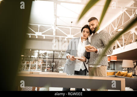 Curious good-looking couple consulting about color of the table Stock Photo