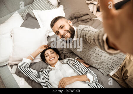 Contented good-looking man with lush beard carrying camera Stock Photo