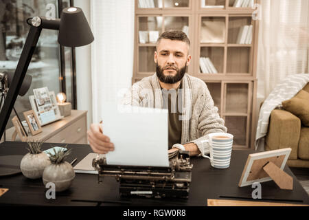 Curious bearded writer checking his writing progress Stock Photo