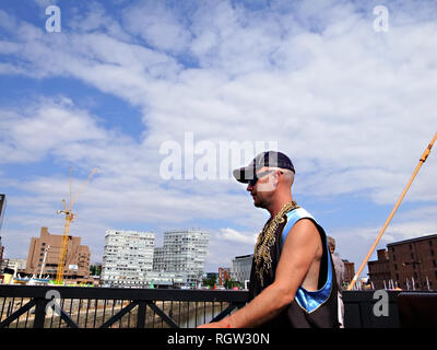 A man wearing gold gangsta-style jewellery and cap walks across a bridge in Liverpool, UK Stock Photo