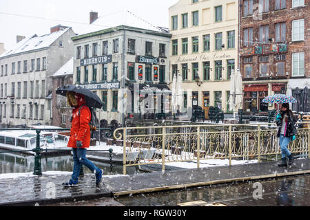 Tourists with umbrellas walking during snow shower / sleet in the city Ghent, East Flanders, Belgium Stock Photo