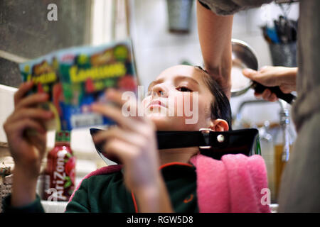 10 year old boy having his hair washed in the kitchen. Stock Photo