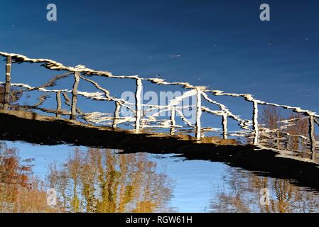 Reflection of a footbridge over water Stock Photo