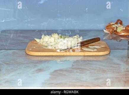 Chef slicing Onion, Allium cepa on the cutting board with a knife. Stock Photo