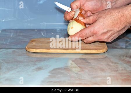 Chef slicing Onion, Allium cepa on the cutting board with a knife. Stock Photo