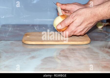 Chef slicing Onion, Allium cepa on the cutting board with a knife. Stock Photo