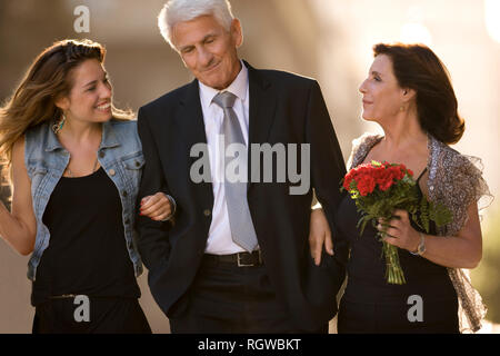 Mature man walking to a formal event with his wife and teenage daughter. Stock Photo