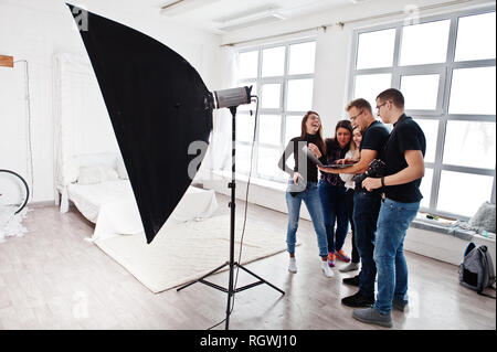 Photographer explaining about the shot to his team in the studio and looking on laptop. Talking to his assistants holding a camera during a photo shoo Stock Photo