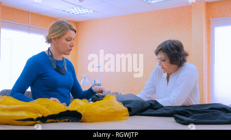 Two professional women tailors, designers discussing new couture collection at atelier, studio. Dressmaking, creativity and tailoring concept Stock Photo