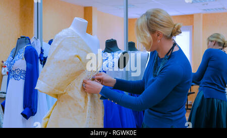 Professional tailor, designer working with new model tailoring dress on mannequin in studio, atelier. Fashion and tailoring concept Stock Photo