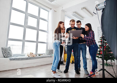Photographer explaining about the shot to his team in the studio and looking on laptop. Talking to his assistants holding a camera during a photo shoo Stock Photo