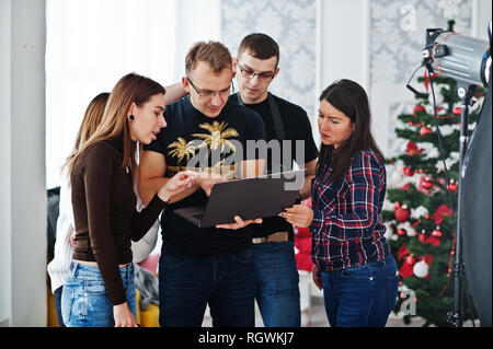 Photographer explaining about the shot to his team in the studio and looking on laptop. Talking to his assistants holding a camera during a photo shoo Stock Photo