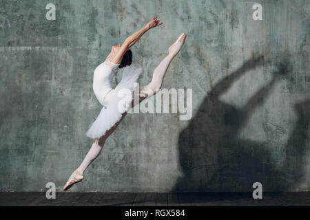 Jumping ballerina . Young beautiful woman ballet dancer, dressed in professional outfit, pointe shoes and white tutu. Stock Photo