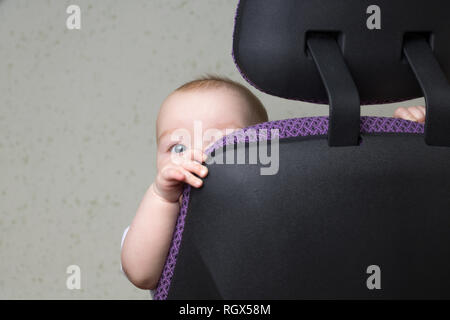 the child is hiding behind the office chair only one eye is visible Stock Photo