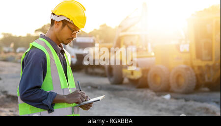 Asian engineer with hardhat using  tablet pc computer inspecting and working at construction site Stock Photo