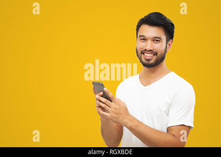 Asian business man handsome man with a mustache, smiling and laughing and using smart phone on yellow background Stock Photo
